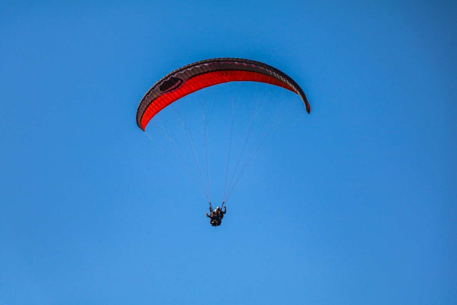 Paragliding wing in flight above terraced hills in Nepal, illustrating the adventure activity planned for the Nuwakot Danda to Butwal route